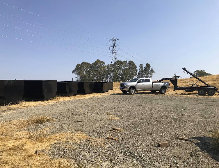Fleet of roll-off dumpsters staged with delivery truck